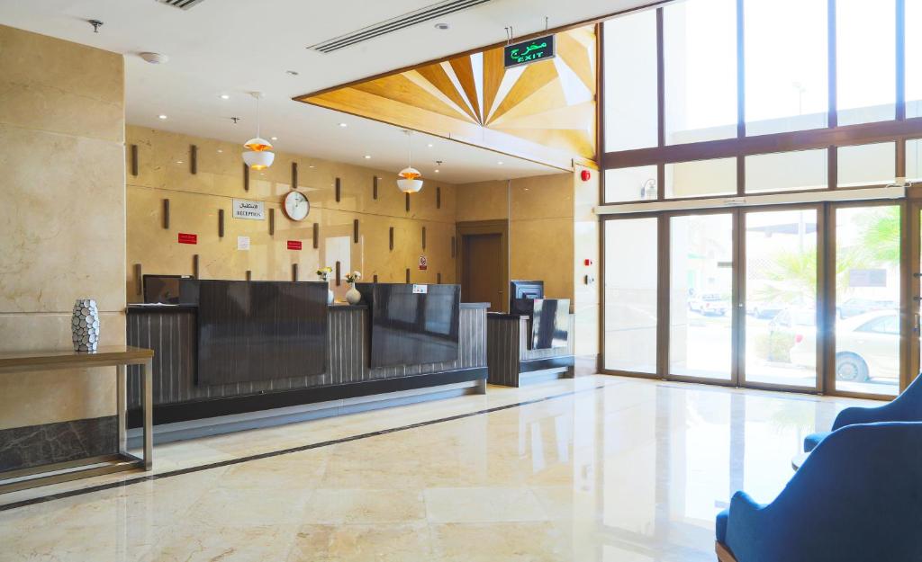 a lobby with a waiting area and a clock on the wall at Safwat Alkhobar Hotel in Al Khobar