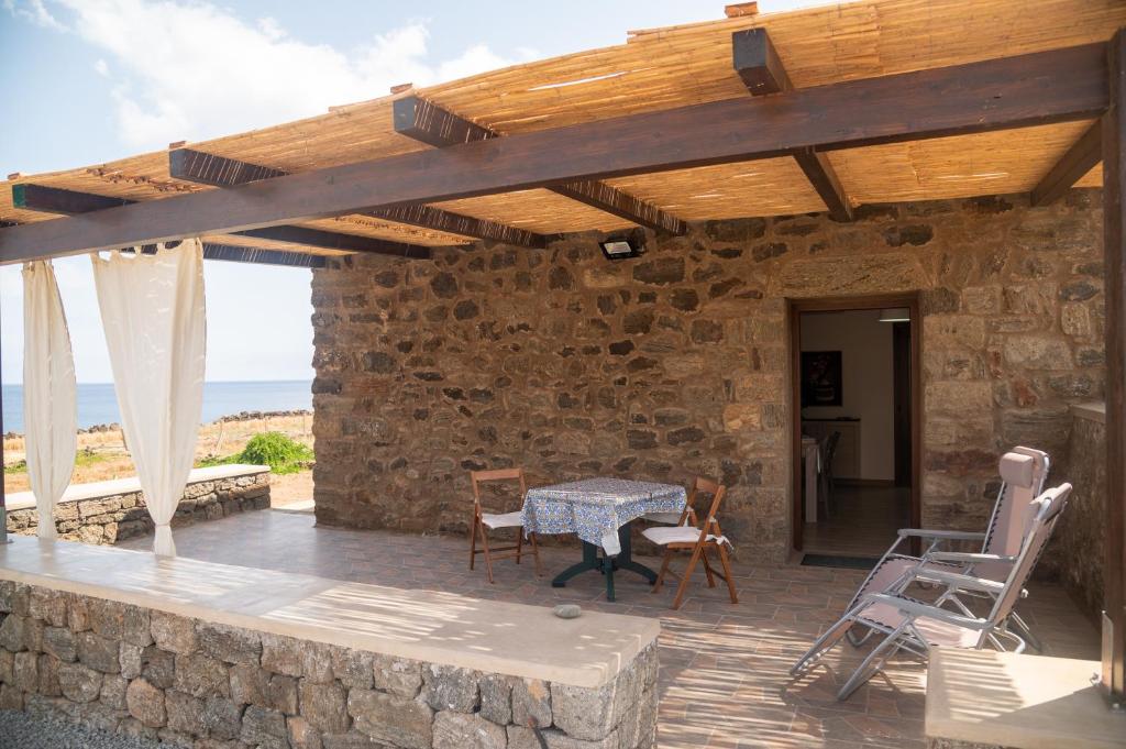 a stone house with a table and chairs on a patio at Dammusu di Turì in Pantelleria