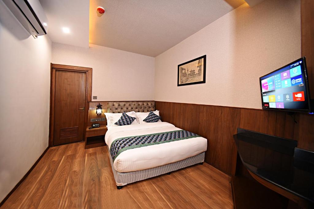 a bedroom with a bed and a flat screen tv at Everest Boutique Hotel in Kathmandu
