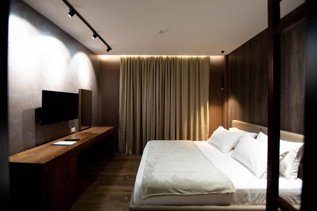 a bedroom with a bed and a desk with a television at Mergan Hotel in Korçë