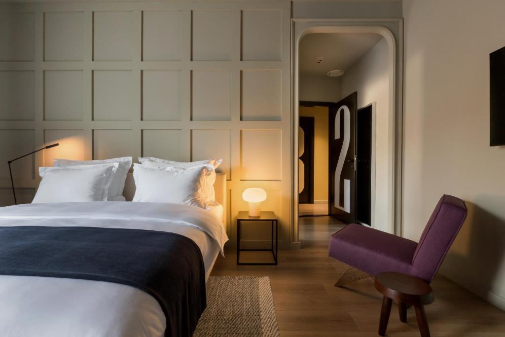 a bedroom with a large bed and a purple chair at Bona Fide Main Square Designer Apartments in Zagreb