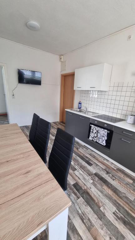 une cuisine avec une table en bois et des chaises noires dans l'établissement Ferienwohnung Nordhausen, à Nordhausen