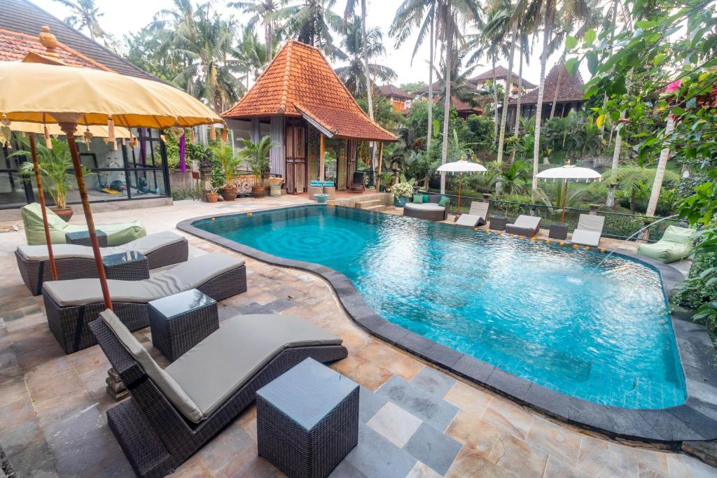 uma piscina num resort com cadeiras e um guarda-sol em Narasoma Homestay & Retreat em Ubud
