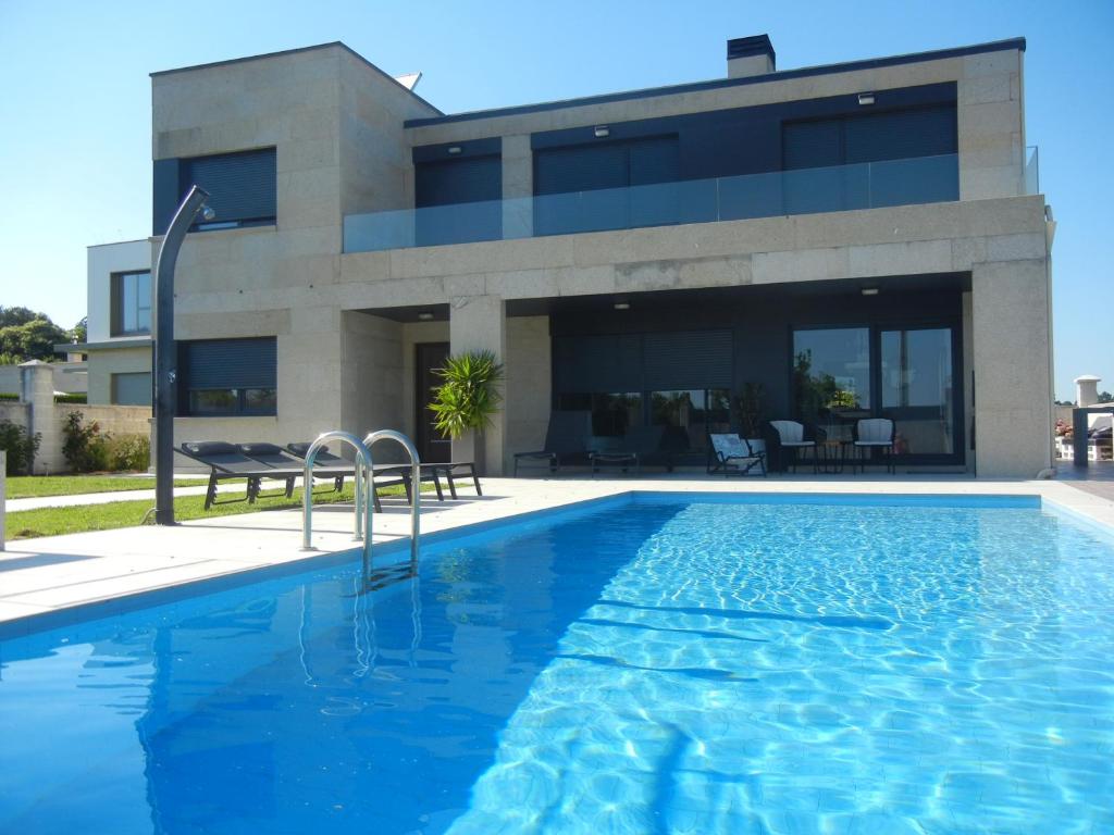 una casa con piscina frente a un edificio en Chalet de diseño moderno en Sanxenxo, en Sanxenxo