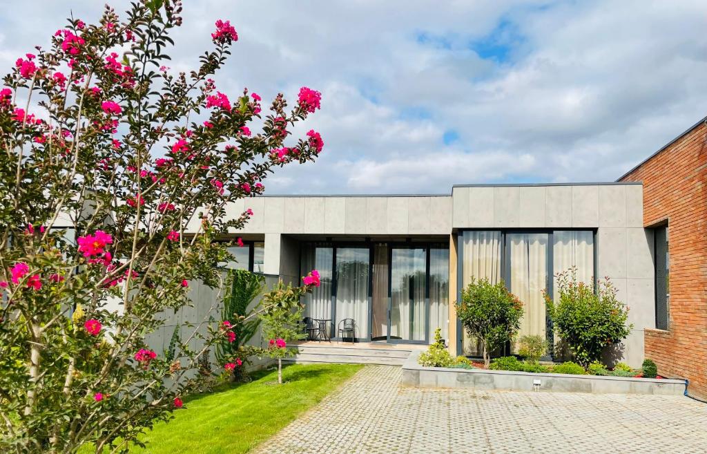 Kachretʼi的住宿－Villa, Kachreti Ambassador Golf Resort，前面有粉红色花的砖砌建筑