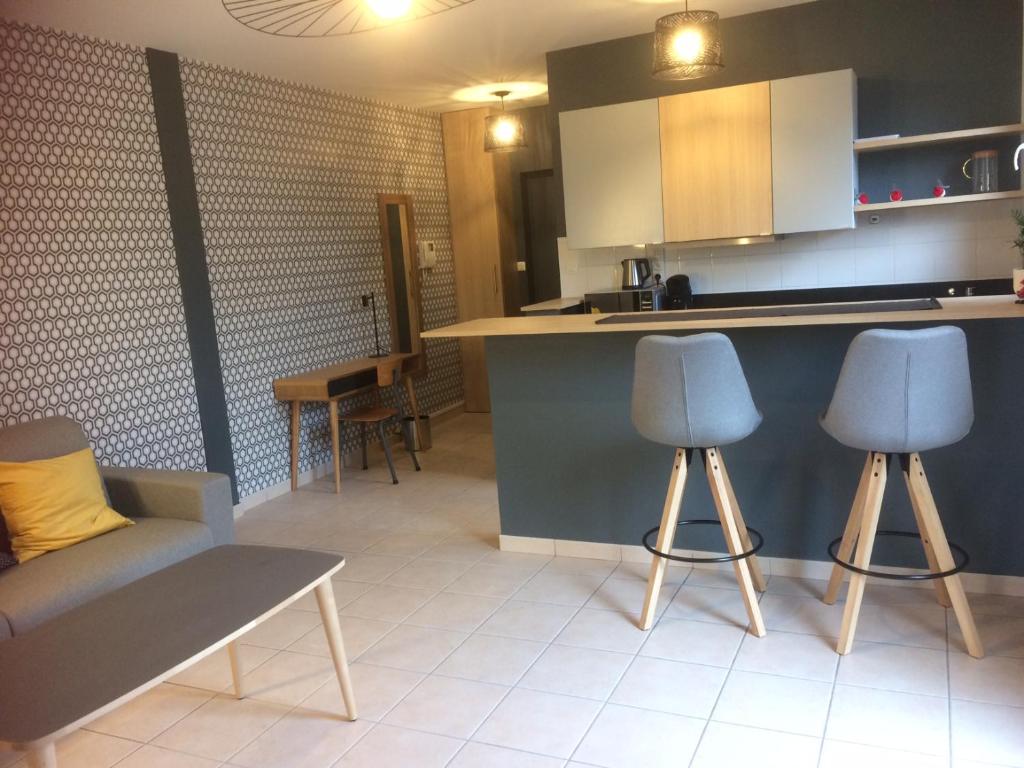 - une cuisine avec 2 chaises bleues et un comptoir dans l'établissement Isabeau appt 2.5, à Cambrai