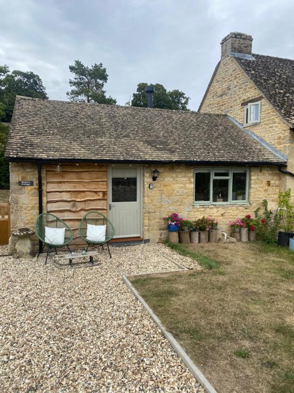 a house with two chairs in front of it at Cosy Cotswolds Self-Contained One Bedroom Cottage in Chipping Norton
