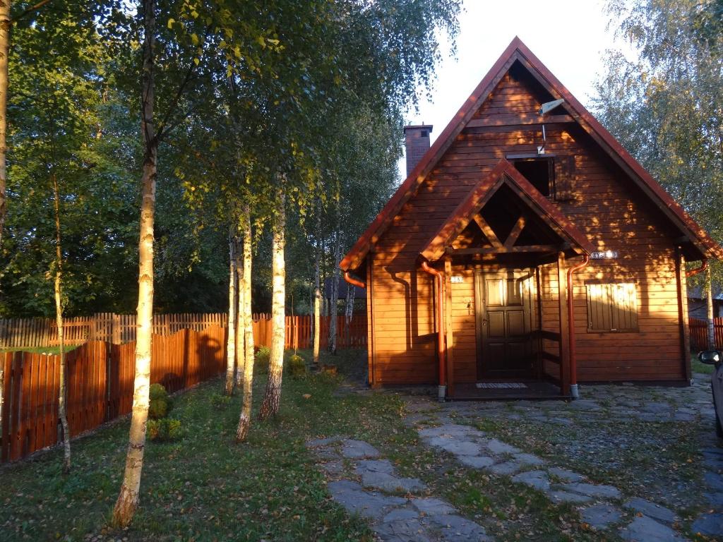 Cabaña de madera con valla y árboles en Siedlisko Czarny Bocian en Giby