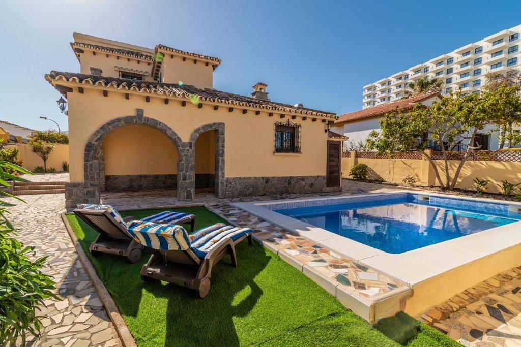 a villa with a swimming pool and two lounge chairs at Villa Paradise in Benalmádena