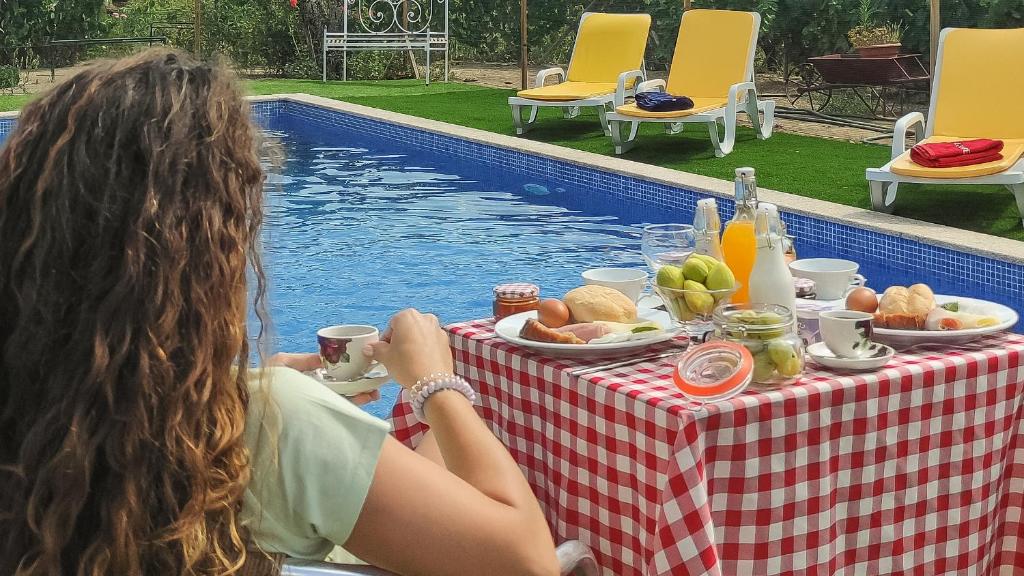 two women sitting at a table near a pool at Quinta dos Padrinhos - Suites in the Heart of the Douro in Lamego