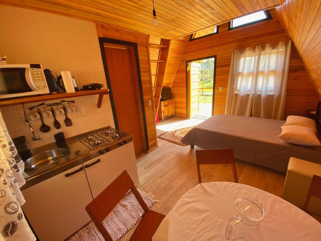 a room with a kitchen and a bedroom with a bed at Pousada Sítio Elias - Chalé 1 in Louro Müller
