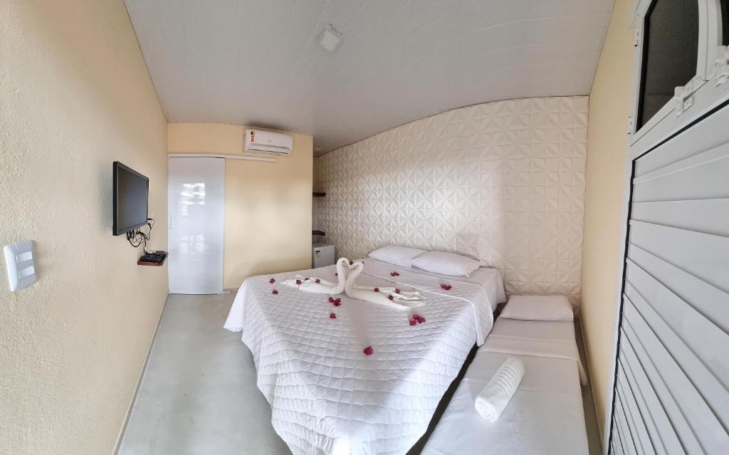 ein kleines Zimmer mit einem Bett mit roten Rosen darauf in der Unterkunft Estalagem Vovô Elias in São Miguel dos Milagres