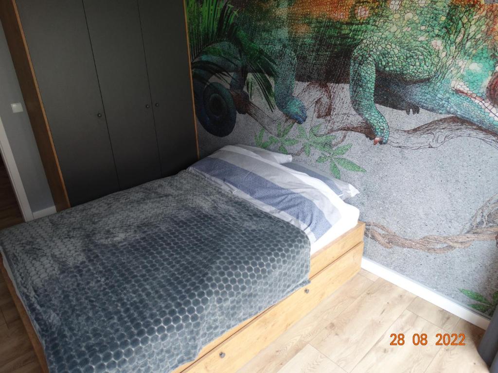 a bedroom with a painting of a dinosaur on the wall at Apartament na Piaskowej in Żarnowska