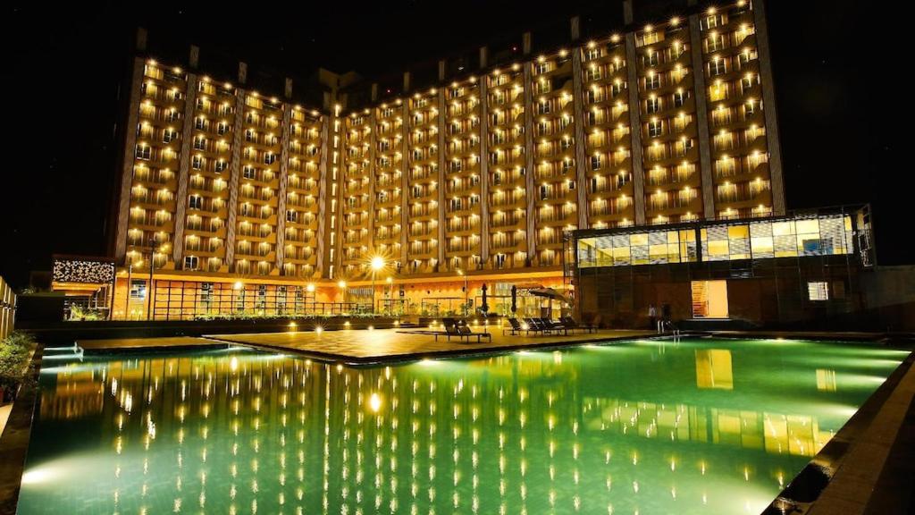 a large building with a swimming pool at night at Weekend Address managed by Global Hospitality in Surat