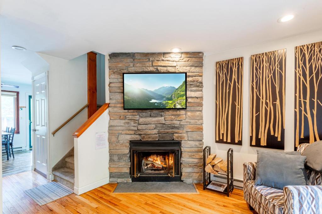 a living room with a fireplace and a tv on a wall at Redwood Retreat in Windham in Windham