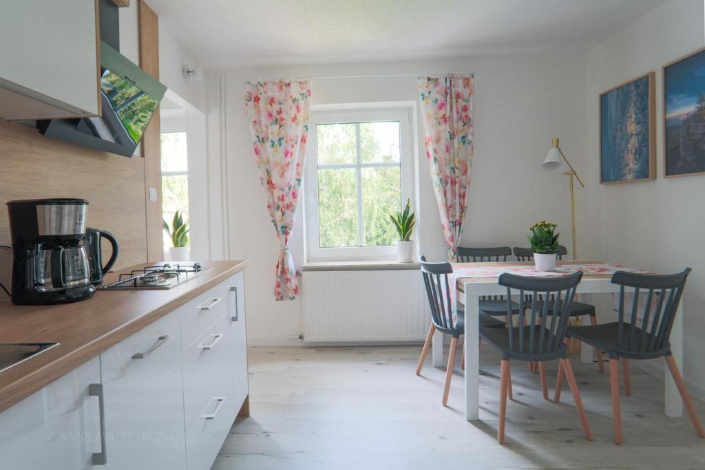 uma cozinha com mesa e cadeiras e uma janela em Apartament Petunia em Duszniki Zdrój