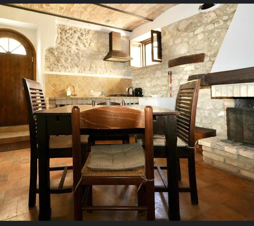 y cocina con mesa de madera, sillas y fogones. en Il Minotauro B&B a 5 minuti da Popoli, en Vittorito