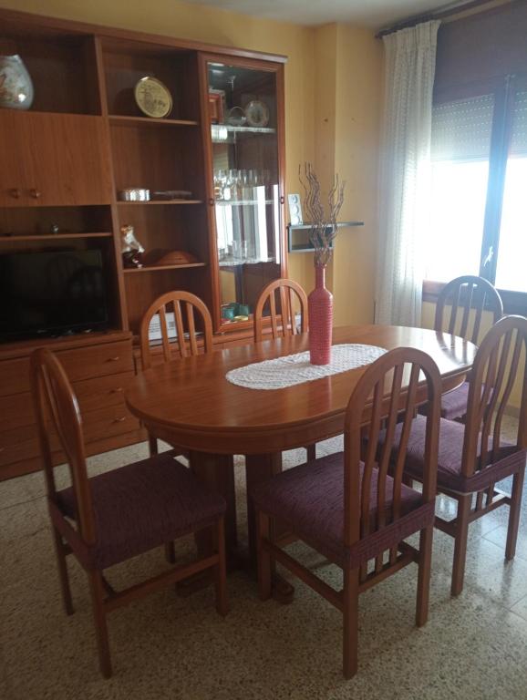 a dining room table and chairs with a table and a tv at Can Molone in Cornudella