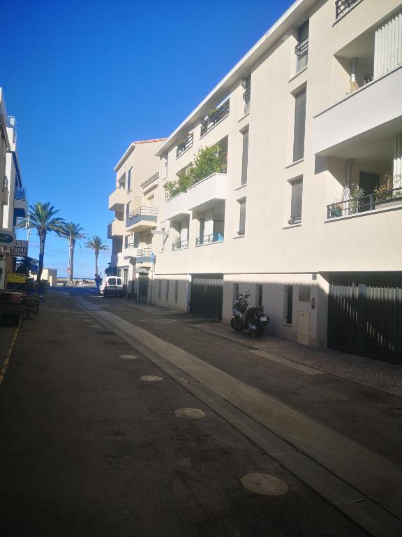 une rue vide devant un bâtiment blanc dans l'établissement Magnifique T2 les pieds dans le sable, au Grau-du-Roi