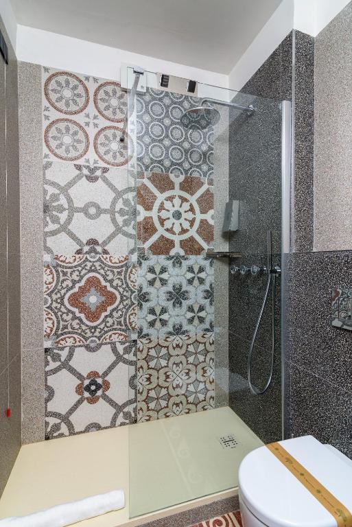 e bagno con doccia, servizi igienici e piastrelle. di Elda Hotel a Vico del Gargano