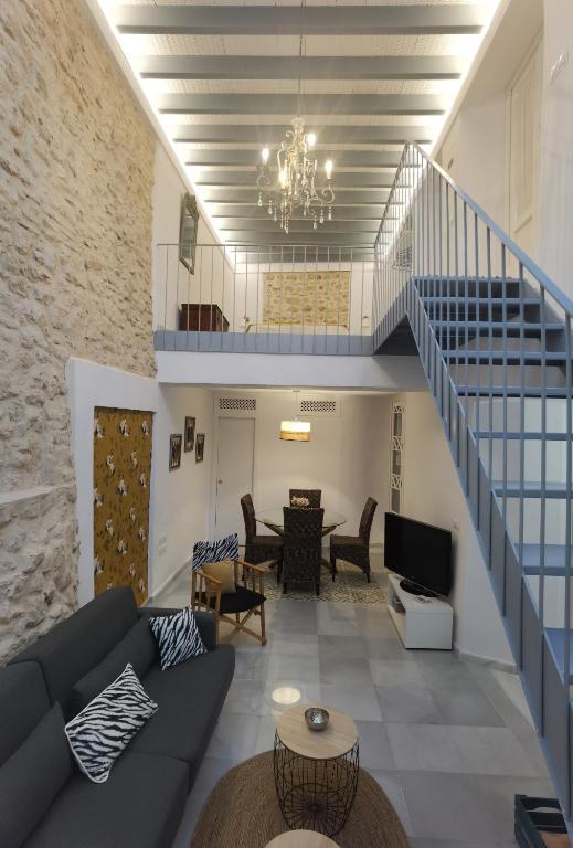 a living room with a couch and a staircase at Ático Plaza 9 by casitasconencantoes in Medina Sidonia