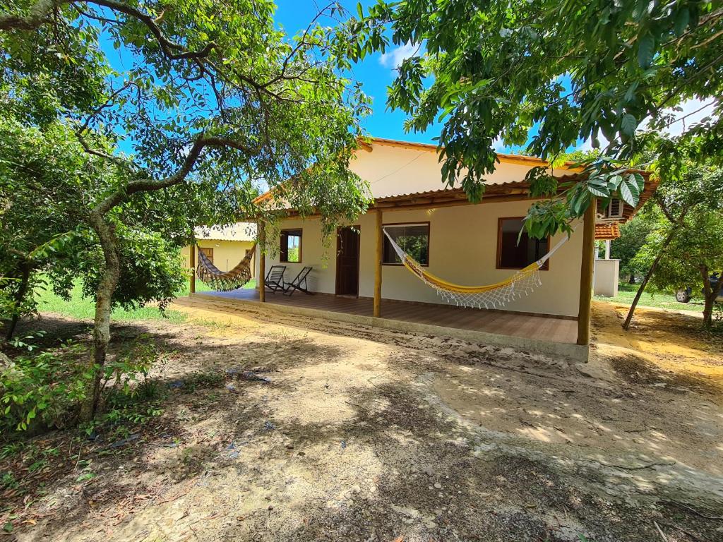a house with a hammock in front of it at Casa Marfim - Privacidade, charme e conforto à 50m do rio in Caravellas