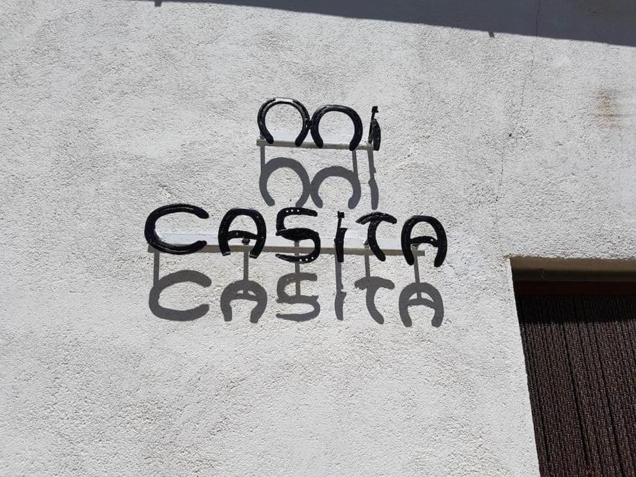 a sign on the side of a white building with scissors on it at 'Mi casita' Típica, Tranquila y Acogedora in Montejo