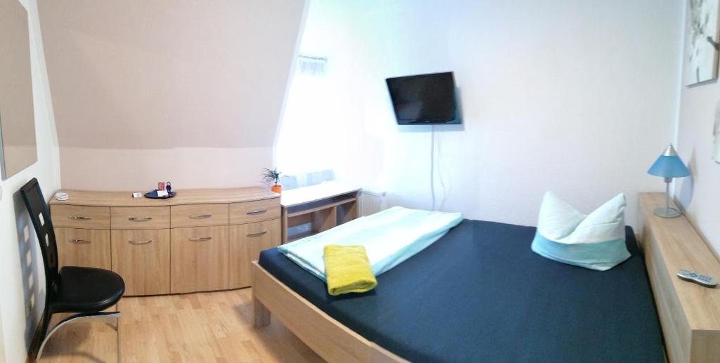 a room with a bed and a desk and a tv at Hotel zum Torwächter in Pritzwalk