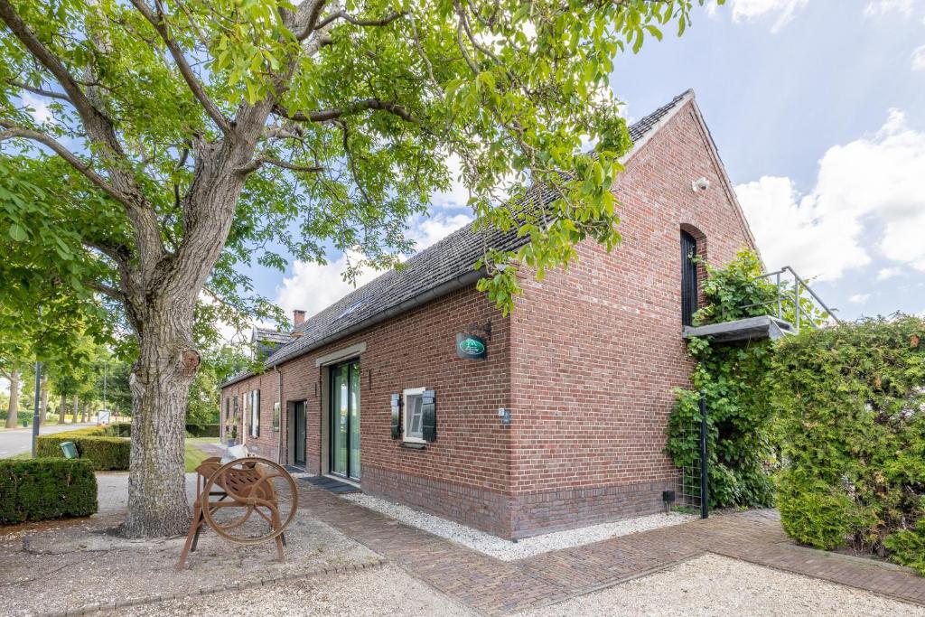 a brick building with a tree and a bench at Gastenverblijf Volkel in Volkel