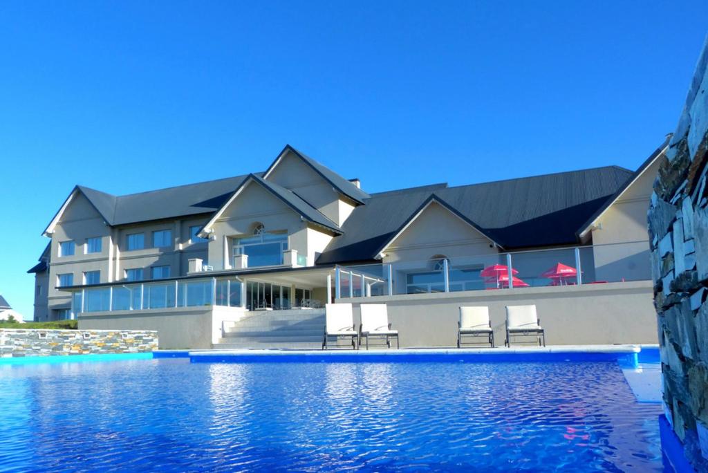 un bâtiment avec des chaises et une piscine dans l'établissement Howard Johnson Hotel Piedras Moras, à Almafuerte