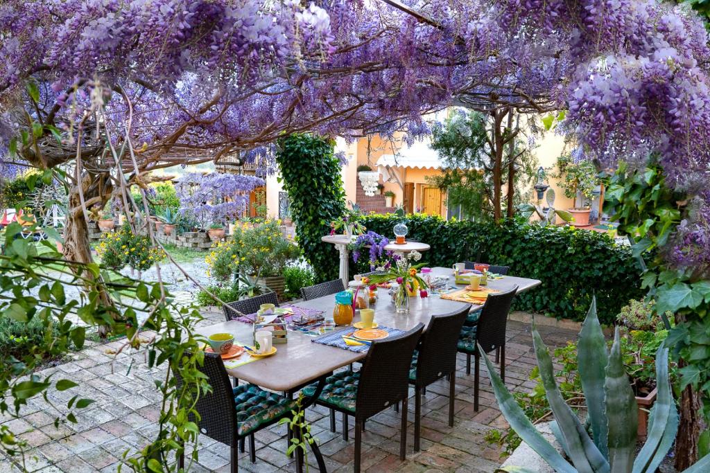 a table in a garden with purple wisteria at B&B Glicine in Ancona