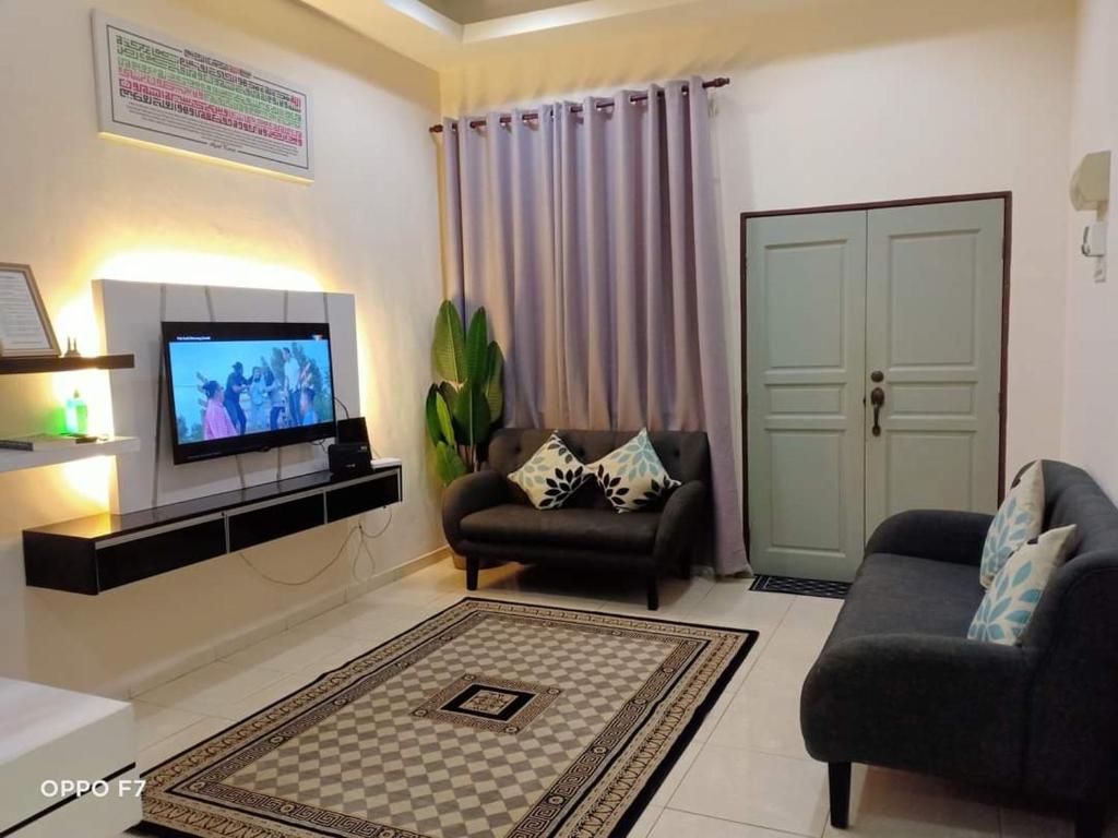a living room with two chairs and a flat screen tv at Melissa Homestay Merlimau in Merlimau