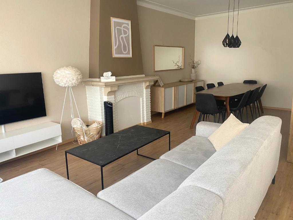 un soggiorno con divano, TV e tavolo di Cosy and Fully Equipped Apartment near Antwerp ad Anversa