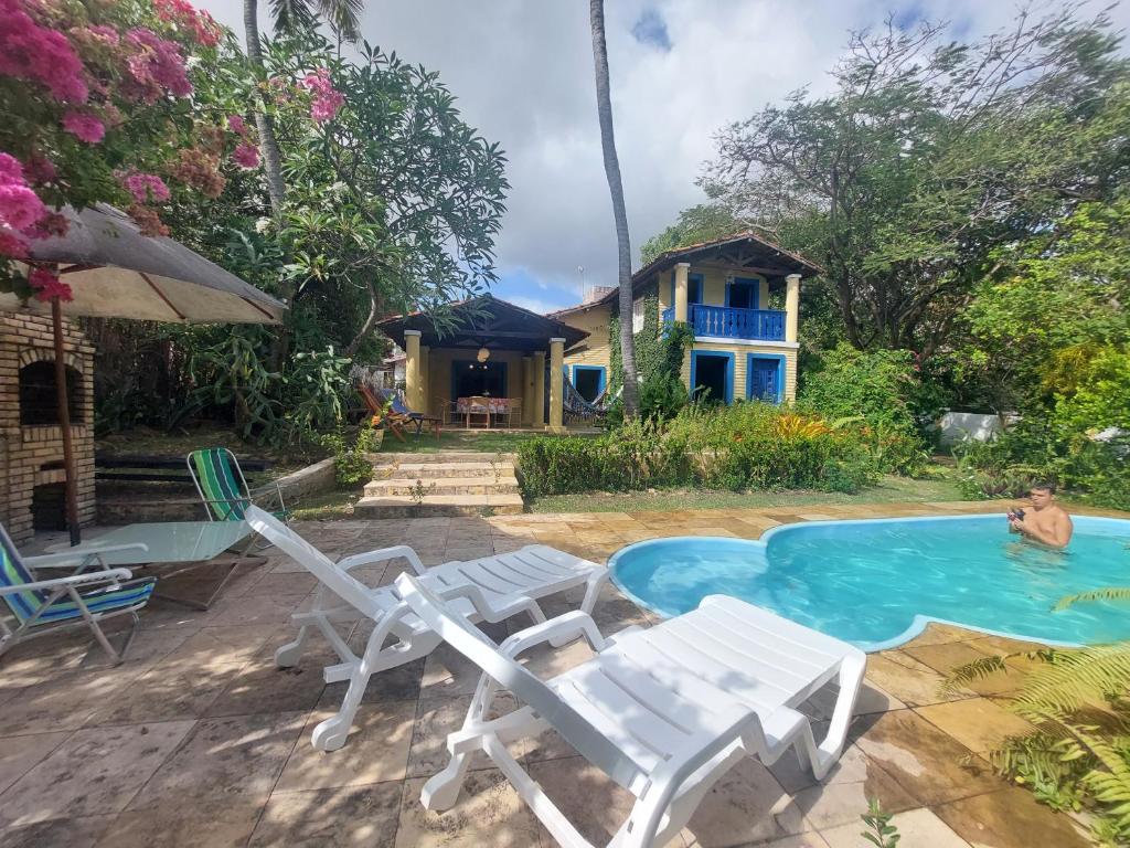 泰巴的住宿－Casa Jasmine Taíba，一个带椅子的游泳池和一个背景房子