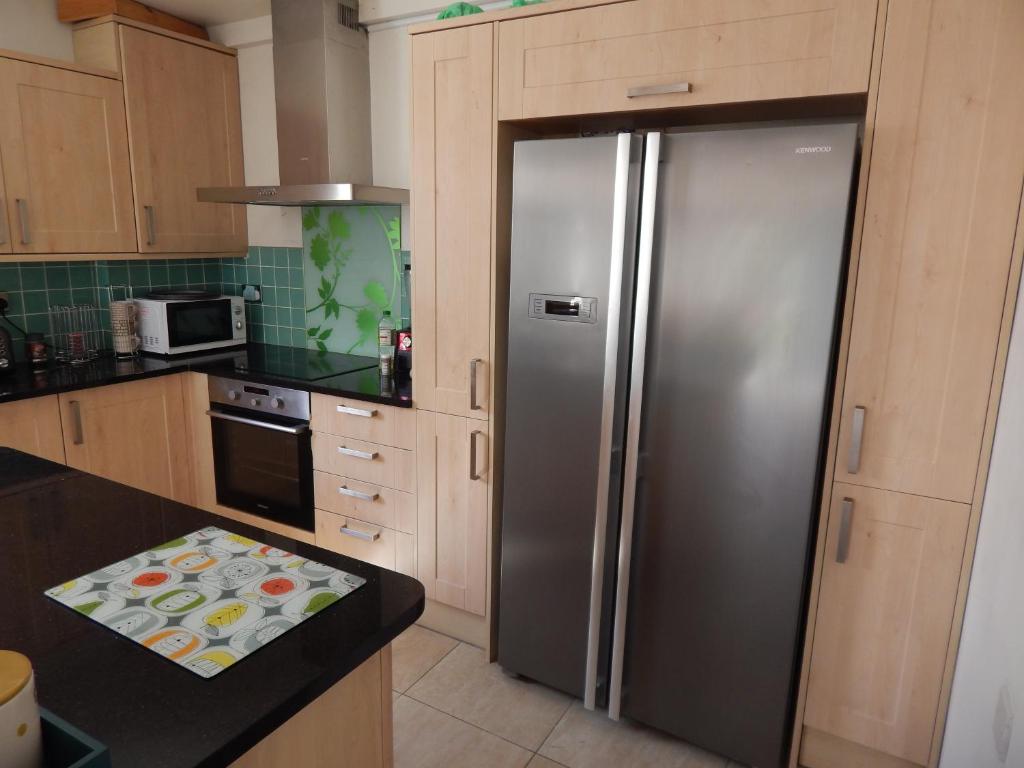 a stainless steel refrigerator in a kitchen with wooden cabinets at Science Park Suite in Cambridge