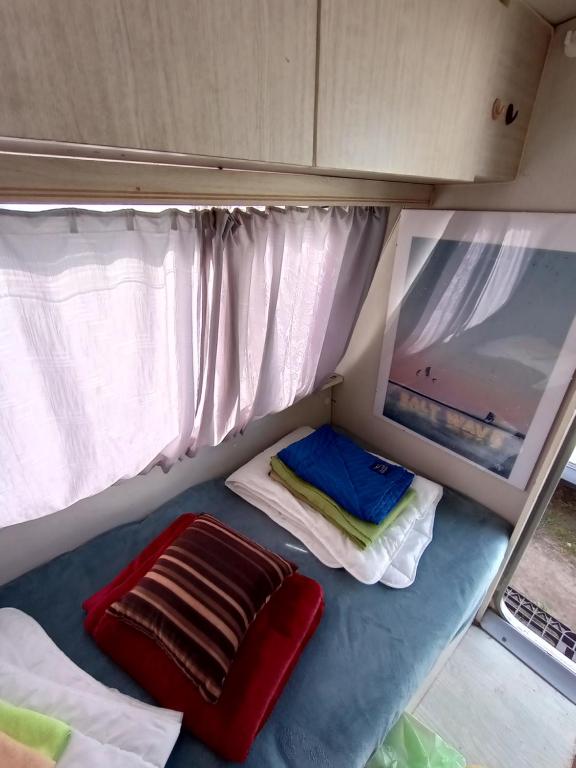 um pequeno quarto com 2 camas e uma janela em Przyczepa Niewiadów Surf Wioska em Jastarnia