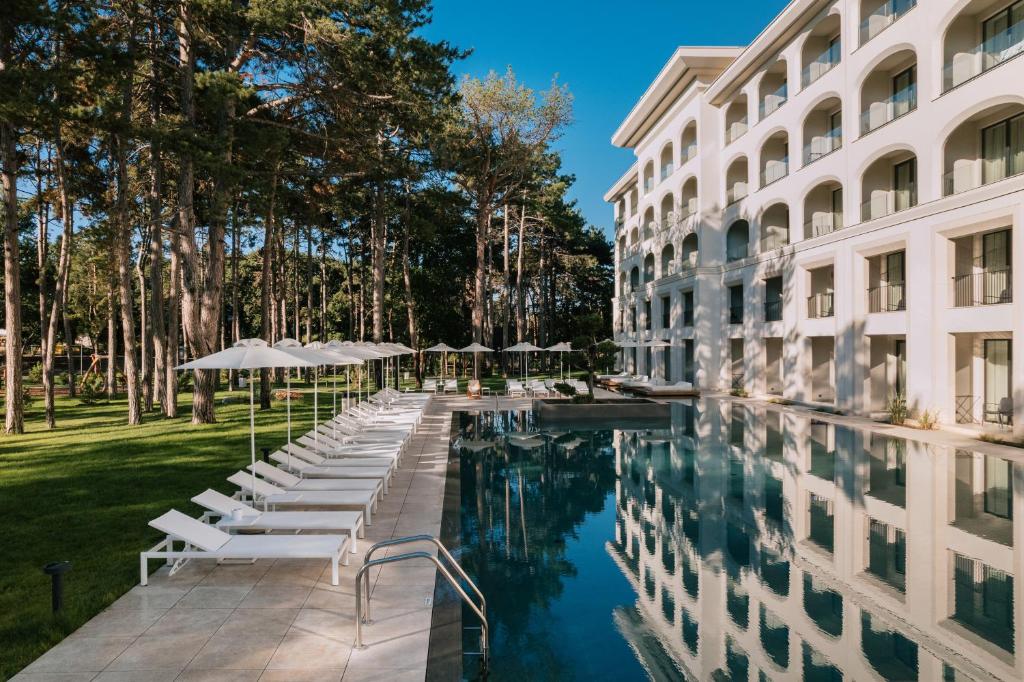 ein Hotelpool mit Stühlen und Sonnenschirmen neben einem Gebäude in der Unterkunft Ensana Aquahouse in Sweti Konstantin