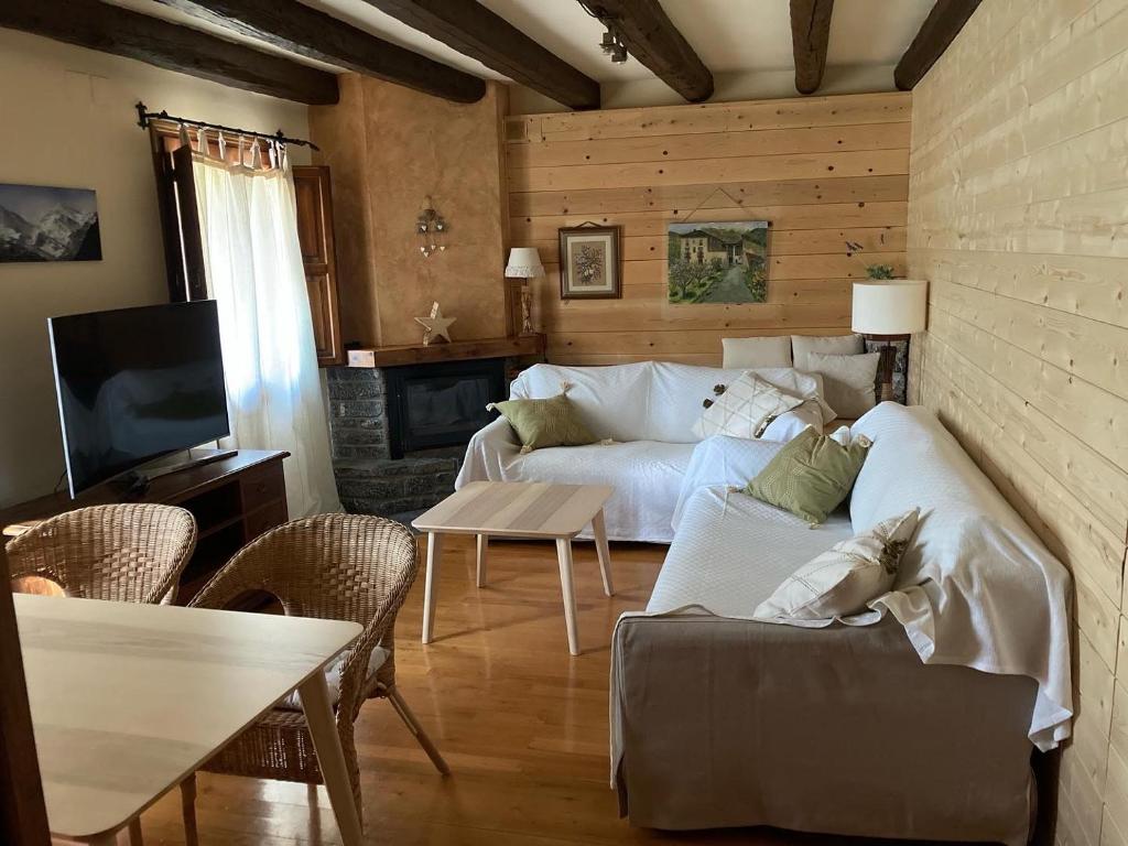 a living room with a white couch and a fireplace at El Cau de Cal Quimet in Rialp