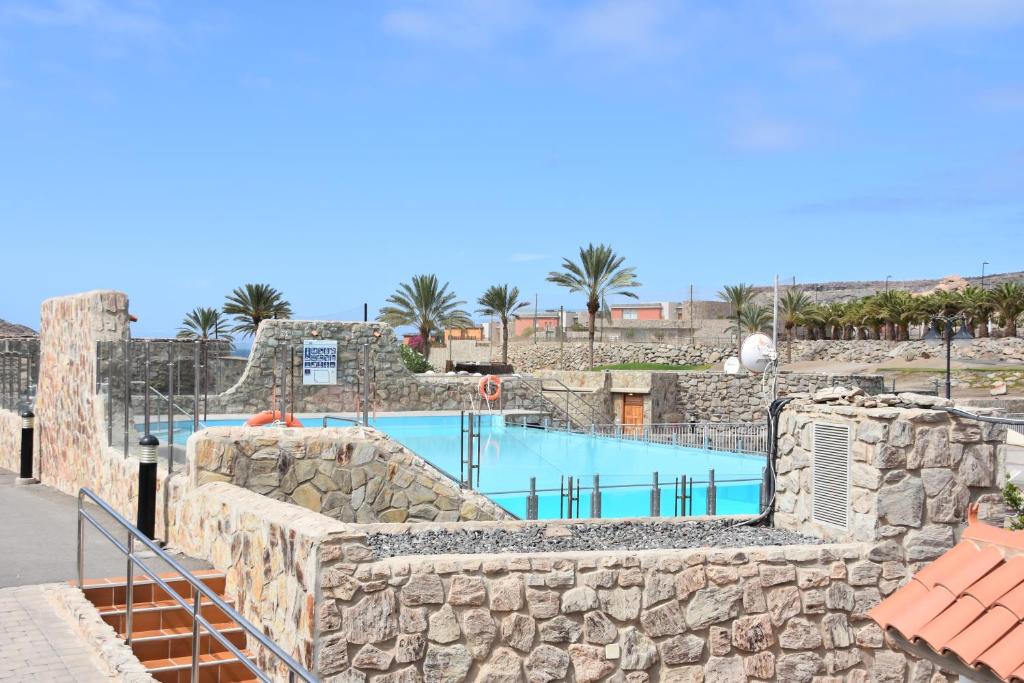 a swimming pool in a resort with a stone wall at ELSA TAURO TOPAZ in Mogán