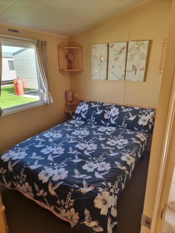a bedroom with a bed with a blue comforter and a window at Palm grove in Chapel Saint Leonards