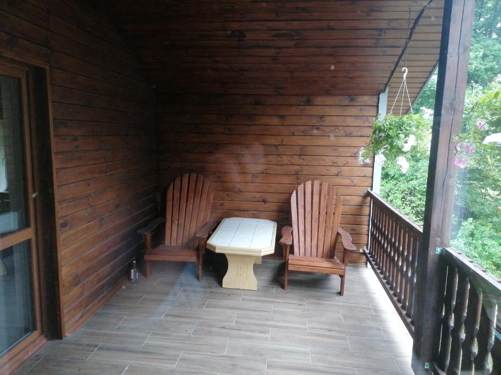 um pátio com 2 cadeiras e uma mesa num alpendre em Osada leśna em Sztabin
