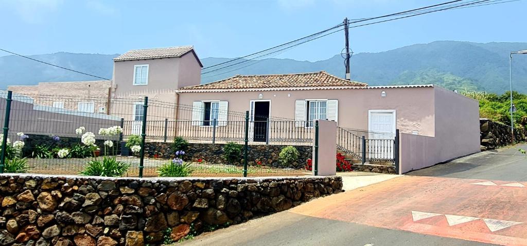 een roze huis met een hek en een stenen muur bij Casa Los Agapantos in Breña Alta