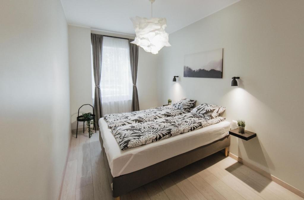 1 dormitorio con cama y lámpara de araña en Rozenstein design apartment, en Brocēni