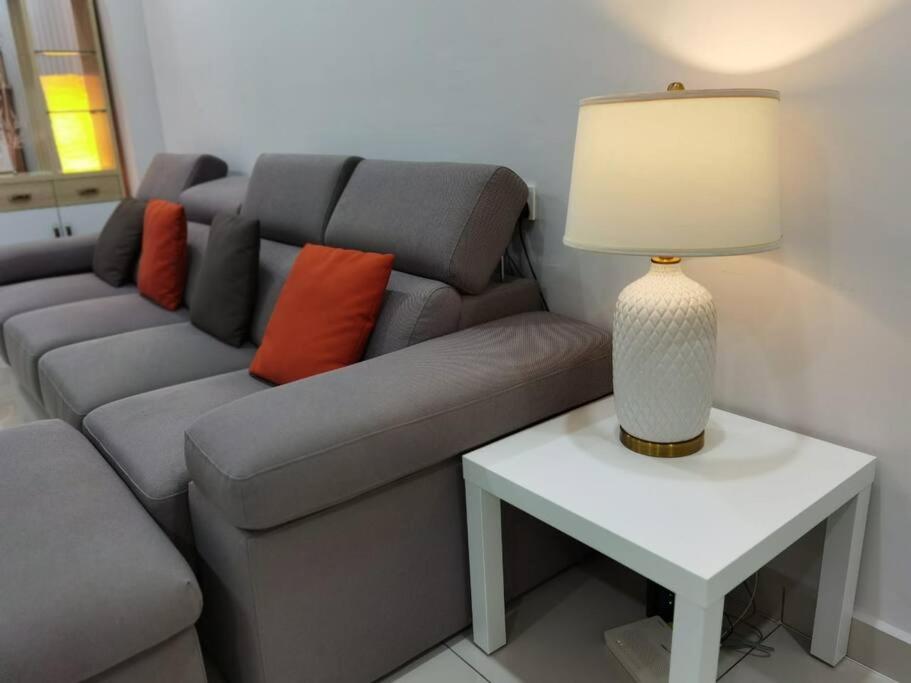 een woonkamer met een bank en een tafel met een lamp bij SUMMERSET 8PAX 3BR LUXURY SEAVIEW SUITE ROOM in George Town