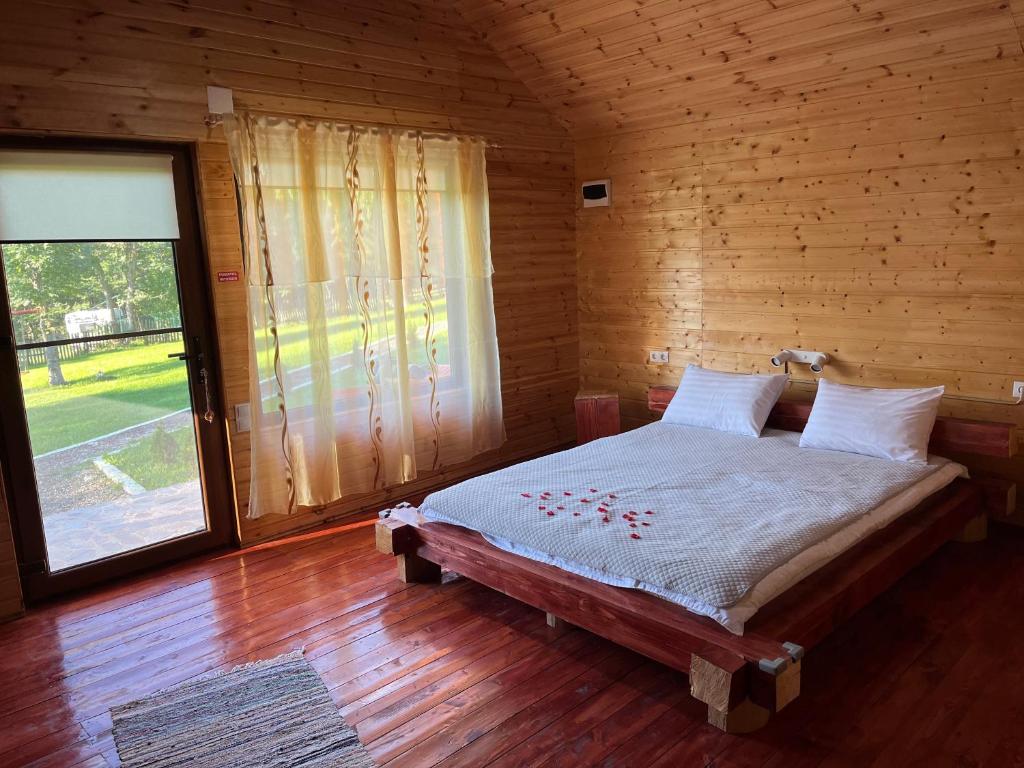 a bedroom with a bed in a wooden room with a window at Complex turistic Traisteni din Valea Doftanei in Podu lui Neag