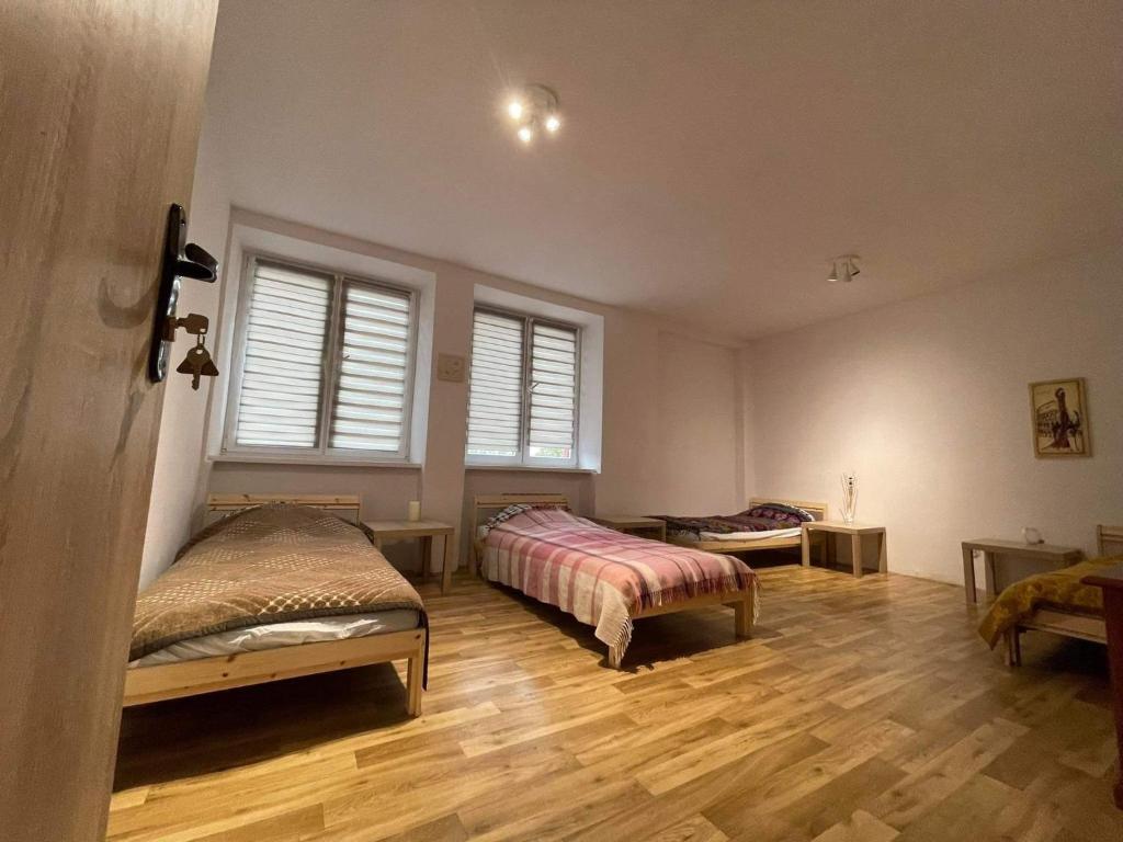 1 dormitorio con 2 camas, suelo de madera y ventanas en Gościniec Biebrzański en Lipsk