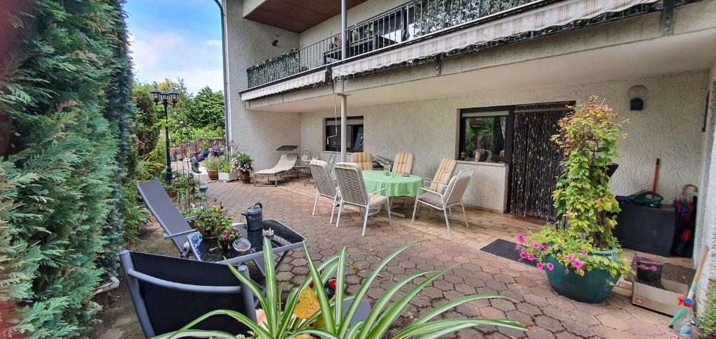 une terrasse avec une table verte, des chaises et des plantes dans l'établissement Schöne Ferienwohnung mit Terrasse und Garten, à Überherrn