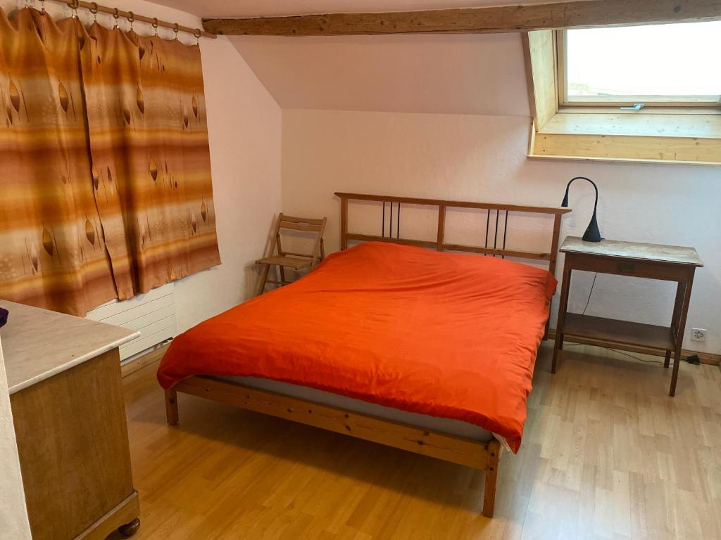 a bedroom with a bed with an orange blanket at A la Maladière in Neuchâtel