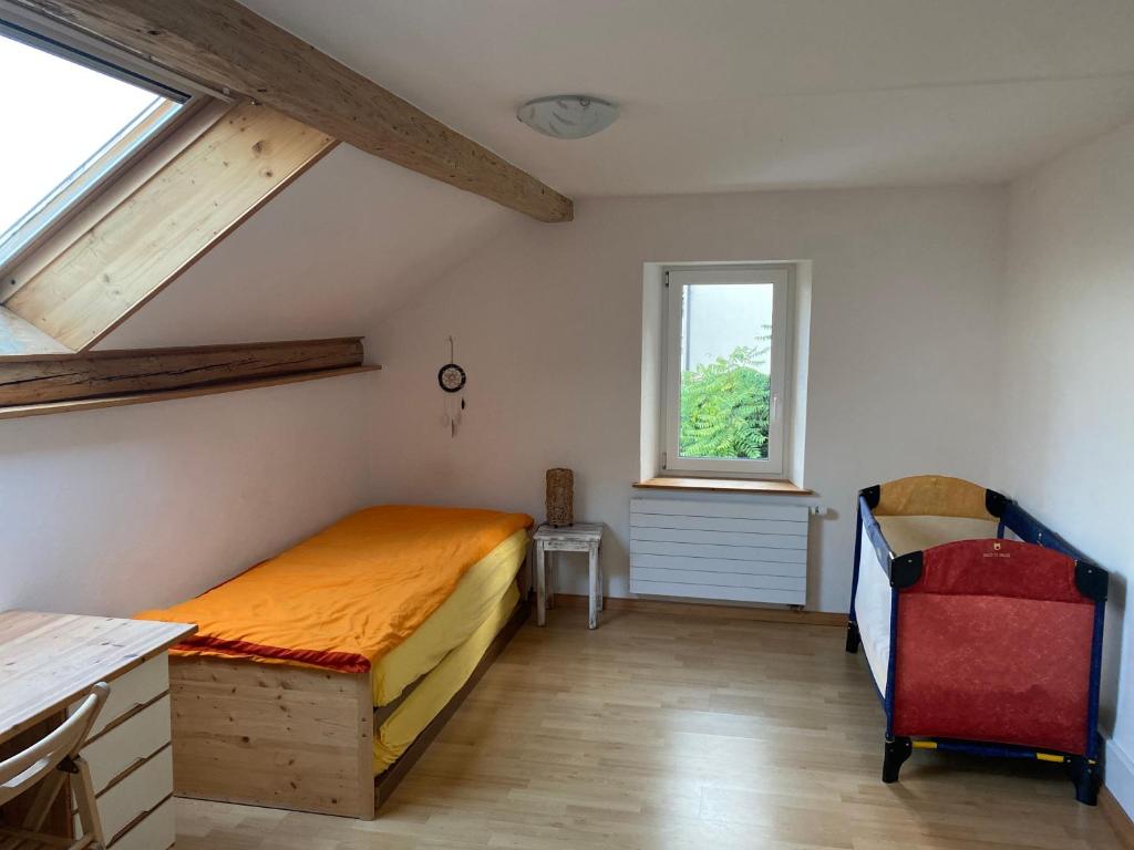 a bedroom with a bed and a desk and a window at A la Maladière in Neuchâtel