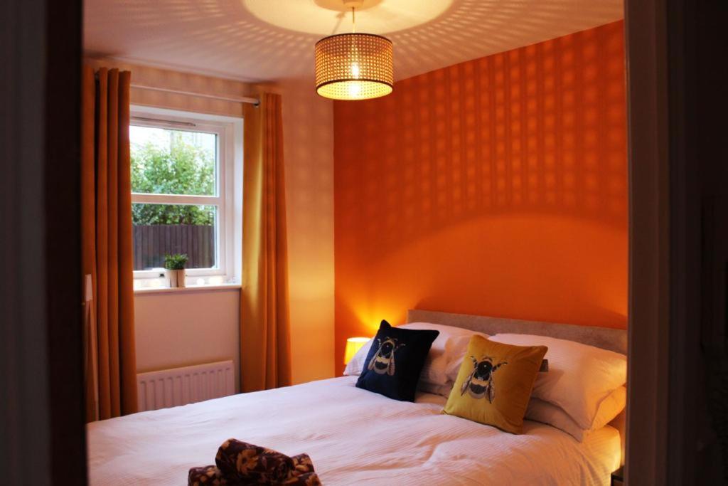 a bedroom with a bed with an orange wall at Cheery Craigie ground floor apartment in Perth